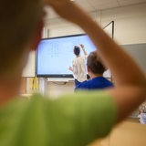 Eine Lehrerin schreibt eine Mathematikaufgabe auf eine digitale Schultafel im Klassenraum einer 4. Klasse einer Grundschule in der Region Hannover. 
