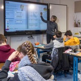 Lehrerin steht vor einer Schulklasse und unterrichtet 