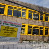 Ein eingezäuntes Schulgebäude mit dem Schild: Betreten der Baustelle verboten.