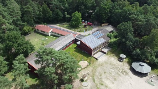 Ein Gebäude eines Schullandheims aus der Luft mit Wald im Hintergrund.