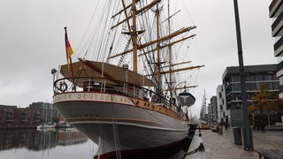 Ein großes Segelschiff liegt an einem Pier.