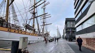 Ein Schiff liegt am Kai vor einer Häuserreihe.