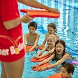 Kinder in einem Schwimmbad, im Vordergrund Frau mit Schriftzug "Bremer Bäder"