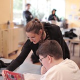 Eine junge Frau hilft einem Schüler in der Schule bei der Erledigung seiner Aufgaben.