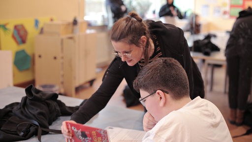 Eine junge Frau hilft einem Schüler in der Schule bei der Erledigung seiner Aufgaben.