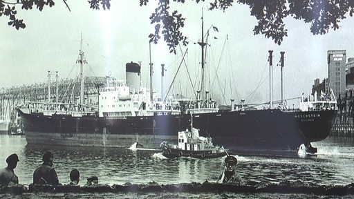 Ein schwarz-weiß Bild von einem Schiff in einem Hafen.