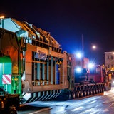 Ein Schwerlasttransport fährt nachts durch eine Stadt.