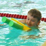 Ein Junge schwimmt mit einer Pool-Nudel.