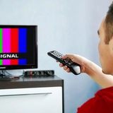 Ein Mann sitzt mit einer Fernbedienung vor dem Fernseher, auf dem "No Signal" steht (Symbolbild)