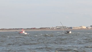 Zu sehen sind eine Segeljacht und ein Boot der Seenotretter auf der Nordsee vor Norderney.