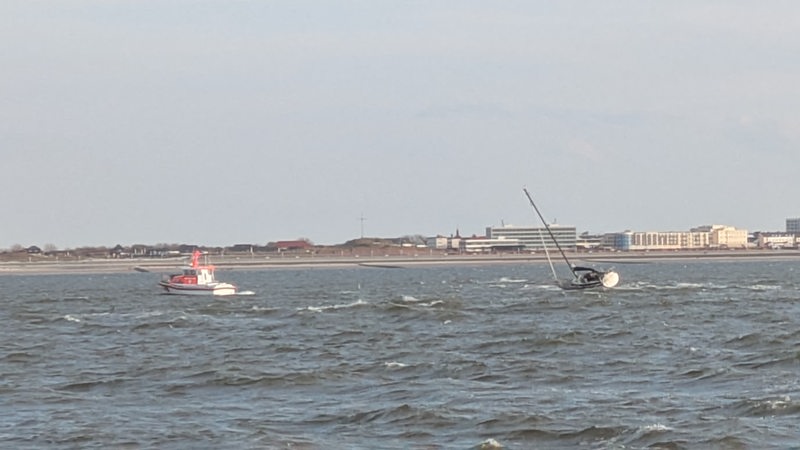 Zu sehen sind eine Segeljacht und ein Boot der Seenotretter auf der Nordsee vor Norderney.