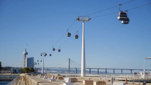 Eine Seilbahn, im Vordergrund eine Brücke mit Sitzgelegenheiten.
