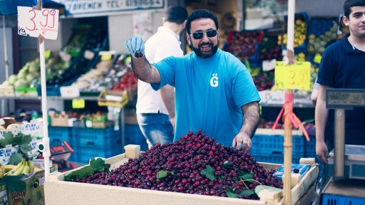 Ein türkischer Mann verkauft Kirschen am Stand des Selam-Markts in der Lindenhofstraße in Gröpelingen