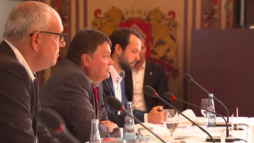 Bremens Bürgermeister Bovenschulte und Finanzsenator Strehl sitzen nebeneinander während einer Pressekonferenz.