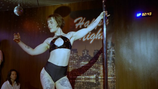 Eine Schuaspielerin tanzt in einer Rolle als Sexarbeiterin an einer Stange.