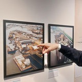 Ein Mann zeigt auf ein Hafen-Foto an der Wand.