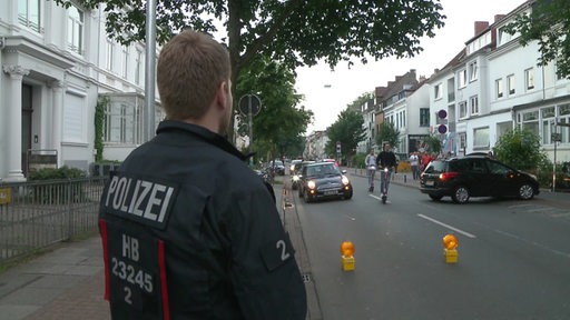 Ein Polizist steht vor einer abgesperrten Straße im Viertel.