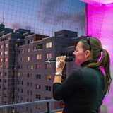 Eine Sängerin mit Mikrofon steht auf einem beleuchteten Balkon bei Nacht