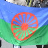 Menschen halten die Flagge der Sinti und Roma während einer Feierlichkeit auf der Straße (Archivbild)