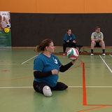 Eine Frau hat einen Volleyball in der Hand.