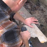 Ein Mann sägt einen Umriss eines Fisches in ein Skateboard.