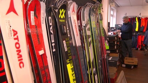 Viele Skier stehen in einem Geschäft an einer Wand.