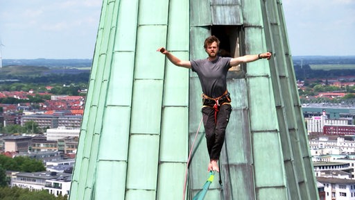 Ein Mann balanciert von einer Spitze des Bremer Doms zur anderen. In 80 Metern Höhe.