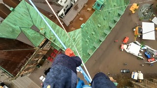 Ein Mann balanciert auf einer Slackline über den Domshof.