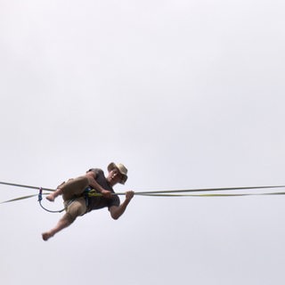 Ein Mann hängt an einer Slackline.