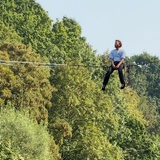 Ein Slackliner balanciert auf einem Seil über einen Fluss.