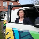 Eine Frau blickt durch das Fenster einer geöffneten Autotür.
