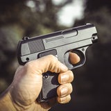 Männerhand mit Waffe.