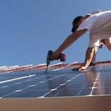 Solarplatteninstallateure befestigen Solarpanele auf einem Dach.