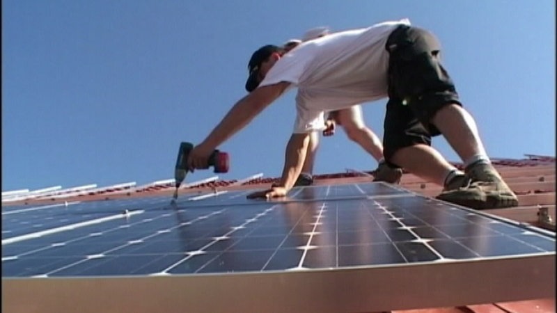 Solarplatteninstallateure befestigen Solarpanele auf einem Dach.