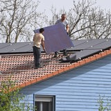 Einfamilienhaus mit Photovoltaikanlage:Arbeiter bei der Montage von Solarpanels auf einem Hausdach. Solarzellen,Solarmodule, Wohnhaus, Solarstrom,Solarenergie ?