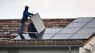 Bauarbeiter bringen eine Solaranlage auf einem Haus an.