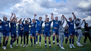 Die Mannschaft des Bremer SV steht hüpfend und mit hochgereckten Armen jubelnd vor den Fans nach dem Pokal-Sieg.