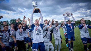 Die Fußball-Mannschaft des Bremer SV beim jubelnden Gruppenbild nach dem Pokalsieg.