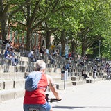 Menschen sitzen auf den Stufen an der  Schlachte, im Vordergrund eine Fahrradfahrerin