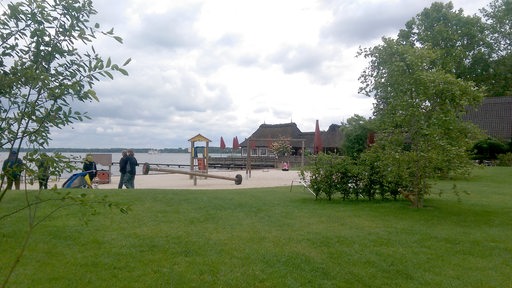 Ein Strand mit Spielplatz an einem See.