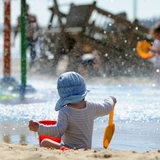 Ein kleiner Junge mit Sonnenmütze spielt bei schönstem Sommerwetter am Weserstrand von Bremerhaven (Bremen). 