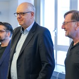 Andreas Bovenschulte steht neben Parteikollegen in einem Konferenzraum.
