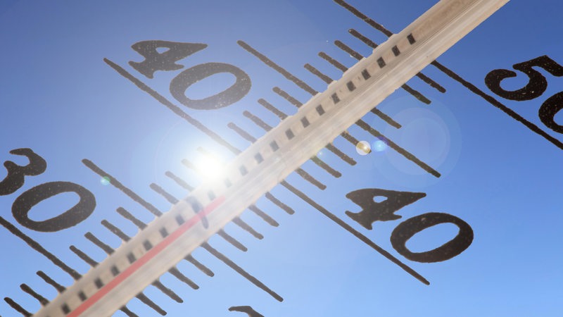 Ein Thermometer zeigt Temperaturen über 35 Grad Celsius an, im Hintergrund blauer Himmel und Sonne