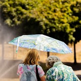 Zwei Frauen schützen sich mit einem Schirm vor der Sonne.