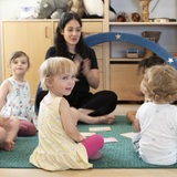 Zwei Erzieherinnen spielen mit Kindern in einer Kinderkrippe.