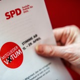 Eine Hand hält die Unterlagen, die SPD Mitgliedern zum Mitgliedervotum zum Koalitionsvertrag zugeschickt bekommen.