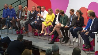 Die sieben Kandidaten-Duos der SPD nebeneinander sitzend auf der Bühne.