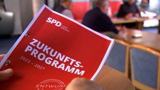 Ein Mann hält das Wahlprogramm der SPD in den Händen.