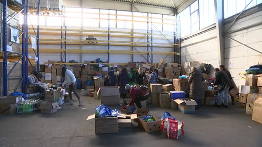 Vereinsmitglieder sortieren Spenden für die ukrainischen Geflüchteten in einer Lagerhalle.