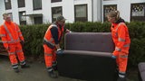 Zwei Menschen tragen ein Sofa vom Straßenrand